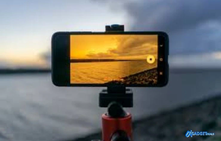 Samsung smartphone mounted on a tripod capturing a sunset over water, demonstrating camera performance and features when choosing the best Samsung phones under $500